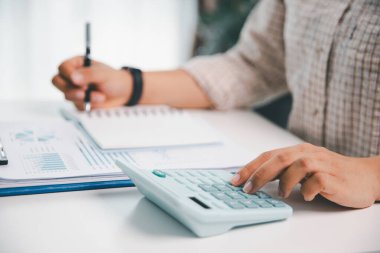 Ofisteki finans raporunu hesaplamak için hesap makinesi kullanan bir muhasebeci. işletme finansmanı, mali belgeleri düzenleyerek vergi hesaplama, gelir yatırımlarını takip etme, elle hesaplama.