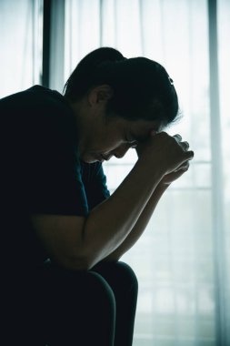 Stresli bir kadın karanlık bir odada tek başına oturuyor, başını eğiyor, depresyonu, endişeyi, umutsuzluğu, yalnızlığı, zihinsel sağlık mücadelesini, tükenmiş ve duygusal acıyı simgeliyor..