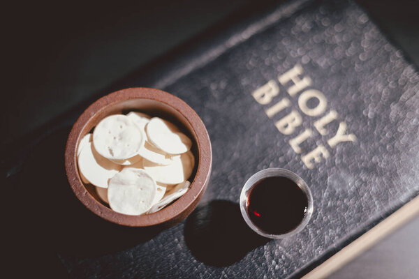 Священный хлеб и чаша вина, возложенные на Священную Библию, символизирующие Вечерю Господню, Евхаристию, жертву Иисуса Христа, христианское поклонение и память о вере.