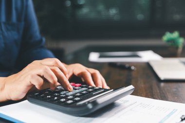 Ofis işkadını eli hesap makinesini çalıştırıyor. Finansal verileri analiz ediyor, masaları sayıyor. muhasebe, iş bütçesi planlaması için mali analiz, hesaplama desteği, finans yönetimi.