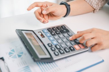 Ofisteki finans raporunu hesaplamak için hesap makinesi kullanan bir muhasebeci. işletme finansmanı, mali belgeleri düzenleyerek vergi hesaplama, gelir yatırımlarını takip etme, elle hesaplama.