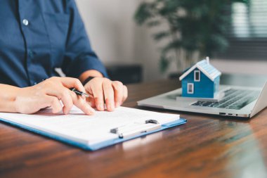 Kadın eli küçük minyatür bir oyuncak evi tutuyor, kendi emlak konseptine taşınma hayalini sembolize eden kadın emlak yatırımını, ipotek planlama, güvenli bir gelecek sigortasını temsil ediyor..