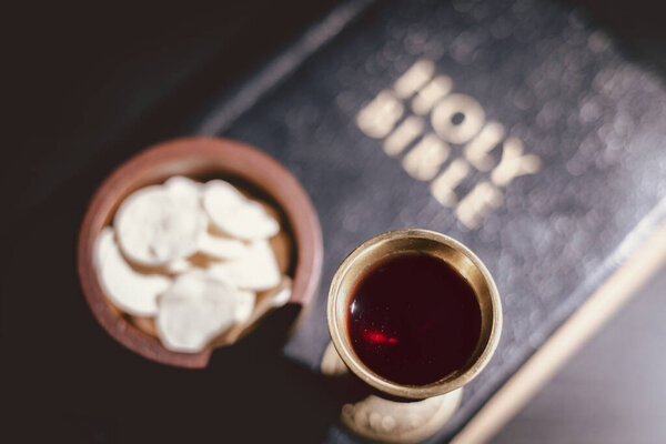 Священный хлеб и чаша вина, возложенные на Священную Библию, символизирующие Вечерю Господню, Евхаристию, жертву Иисуса Христа, христианское поклонение и память о вере.