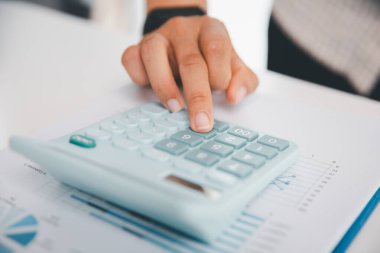 Ofisteki finans raporunu hesaplamak için hesap makinesi kullanan bir muhasebeci. işletme finansmanı, mali belgeleri düzenleyerek vergi hesaplama, gelir yatırımlarını takip etme, elle hesaplama.