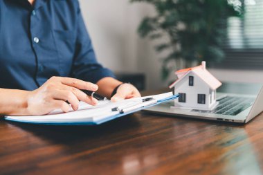 Kadın eli küçük minyatür bir oyuncak evi tutuyor, kendi emlak konseptine taşınma hayalini sembolize eden kadın emlak yatırımını, ipotek planlama, güvenli bir gelecek sigortasını temsil ediyor..