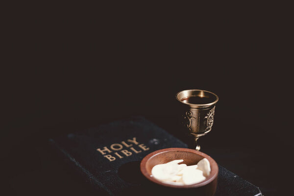 Священный хлеб и чаша вина, возложенные на Священную Библию, символизирующие Вечерю Господню, Евхаристию, жертву Иисуса Христа, христианское поклонение и память о вере.