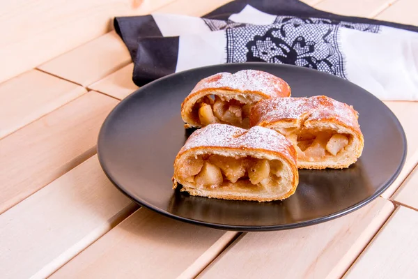 Apfelstrudel Auf Schwarzem Teller Mit Weißer Serviette Auf Holztisch Nahaufnahme — Stockfoto