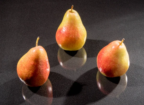 Three pears on a black background with hatching, closeup