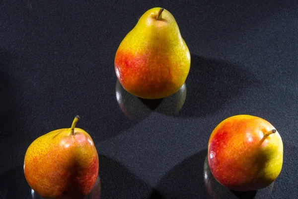 Three pears on a black background with hatching, closeup