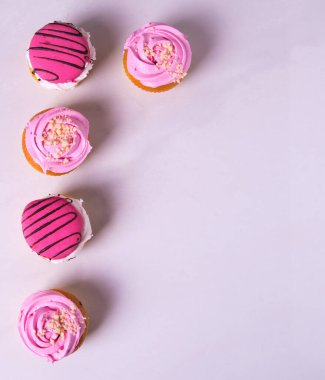 Güzel pembe kekler, kekler, fotoğraf sırasının kenarına dizilmiş, açık bir arkaplanda.