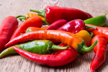  Kırmızı biber, kırmızı, yeşil, sarı eski ahşap bir masaya saçılmış.