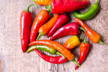  Kırmızı biber, kırmızı, yeşil, sarı eski ahşap bir masaya saçılmış.