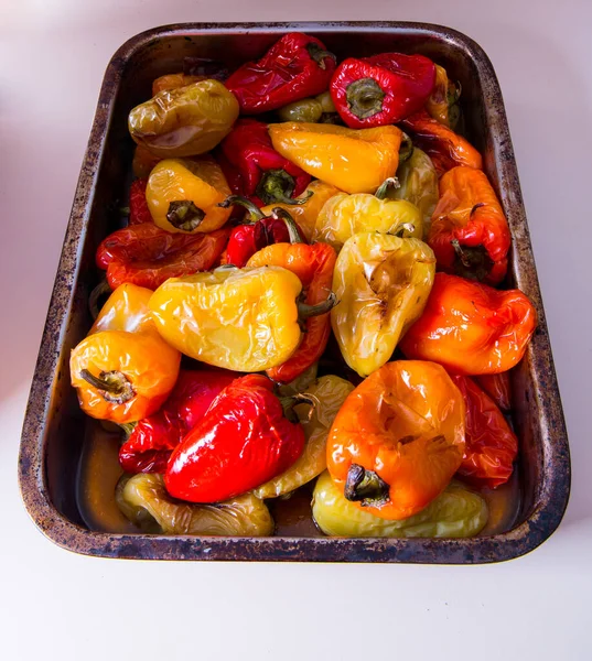 Tatlı biber, biber, kırmızı, sarı büyük metal bir tabakta kızartılmış, beyaz bir arka planda.