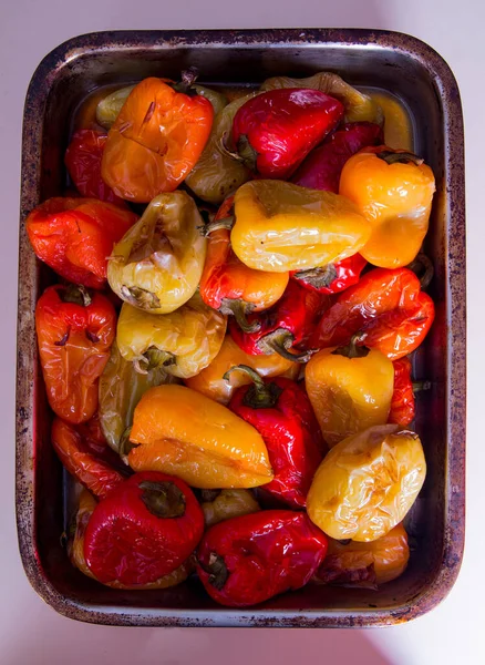 Tatlı biber, biber, kırmızı, sarı büyük metal bir tabakta kızartılmış, beyaz bir arka planda.