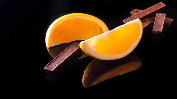 Dwa Kawałki Czekolady Pomarańczach Czarnym Tle — Zdjęcie stockowe