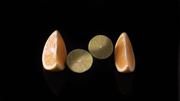 Дві Половинки Свіжого Лайма Дві Скибочки Апельсина Чорному Тлі Крупним — стокове фото