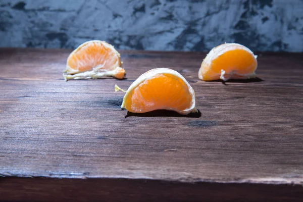 Mandarin slices on an old natural wooden table, side view,close-up,space for text