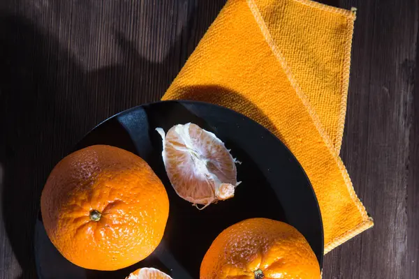 Zwei Mandarinen Mit Scheiben Auf Schwarzem Teller Mit Gelber Serviette — Stockfoto