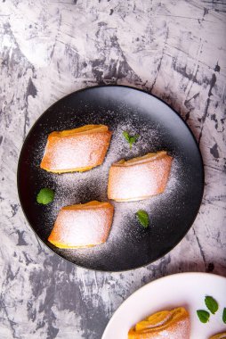 Çörek, nane yapraklarıyla pudralanmış siyah ve beyaz bir tabakta siyah ve beyaz arka planda metin için alanı olan bir pasta.