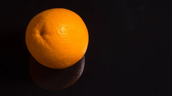 Orange on a black background with reflection, close-up,postcard,background,advertising