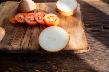 Kırmızı domatesler, dilimlenmiş soğan dilimli domatesler eski, koyu bir ahşap masada, yakın plan.
