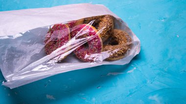 Pembe ve çikolata kremalı donutlar paketin içinde mavi bir arka planda, metin için yer, yakın plan.