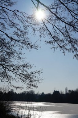 Şubat ayında güneş Wuhlebecken Gölü ya da Wuhlebecken Gölü 'nün üzerinde parlar. Wuhlebecken ya da Wuhlesee, Marzahn-Hellersdorf, Berlin, Almanya, Avrupa 'da bulunan bir göldür.. 