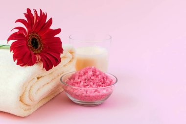 Pembe arka planda Gerbera çiçekleri olan spa ürünleri. Terry havlu, aroma mumu, pembe arka planda banyo tuzu. Flatlay güzellik merkezi konsepti. düz yat