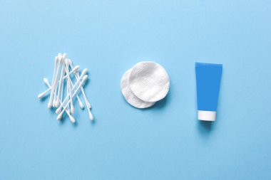 Mavi renkli arka planda kozmetik ürünler. Pamuk pedler, pamuk çubuklar, şişe, makyaj temizleyicisi, mikiler suyu, çamaşır jeli. Makyaj malzemesi için cilt bakımı. Metin için alanı olan minimalizm düzlüğü.