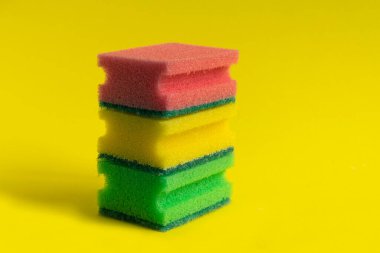 Sarı arka planı temizlemek için sünger. Evi temizleme, toz alma, ev işi. Temizlik işi, üretim