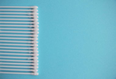 Mavi arka planda pamuk tomurcukları ve süngerler. Plastik pamuklu bez. Üst görüş kulak çubukları. Kozmetikleri kaldırmak için düz konum bileşimi ürünleri.
