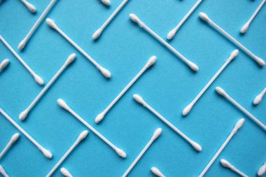 Mavi arka planda pamuk tomurcukları ve süngerler. Plastik pamuklu bez. Üst görüş kulak çubukları. Kozmetikleri kaldırmak için düz konum bileşimi ürünleri.