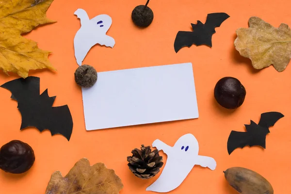 Feliz Halloween concepto de vacaciones. Decoraciones de Halloween, murciélagos y espeluznantes con hojas amarillas de otoño sobre un fondo naranja. Tarjeta con marco para texto. — Foto de Stock
