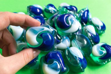 Yeşil arka planda izole edilmiş çamaşır yıkama kapsülleri. Ev işi konsepti. Yıkama ve temizleme. Üst Manzara. düz konum.