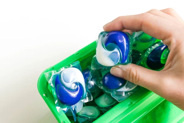 Capsules in hand for washing clothes in a box isolated on white background. Housework concept. Washing and clean things. Top view. flat lay composition.