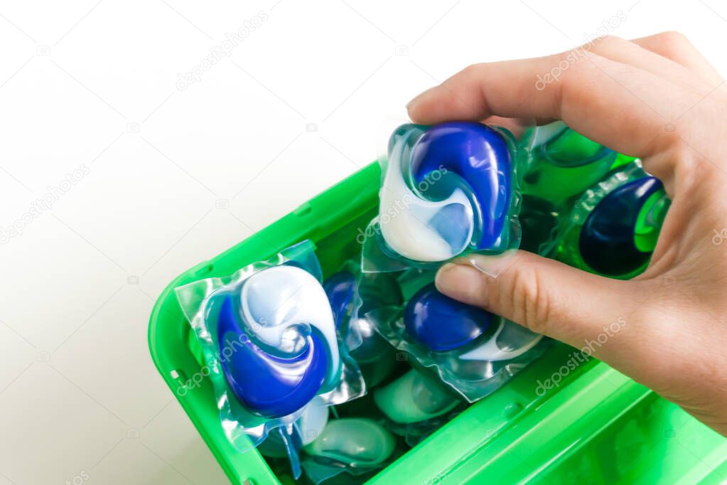 Capsules in hand for washing clothes in a box isolated on white background. Housework concept. Washing and clean things. Top view. flat lay composition.