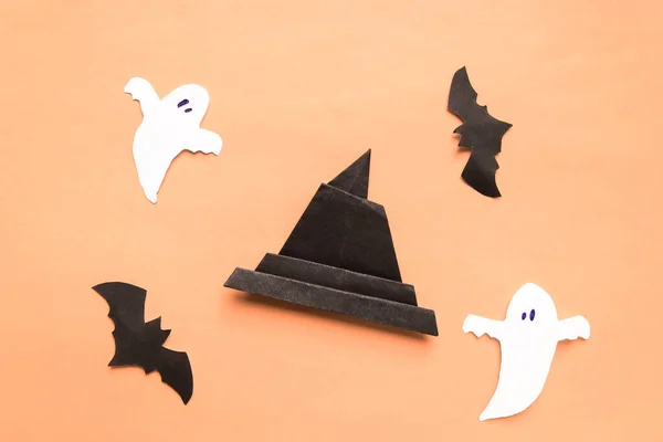 Mutlu Cadılar Bayramı konsepti. Cadılar Bayramı süslemeleri, yarasalar, bej turuncu arka planda ürkütücü ve origami cadı şapkası. Üst Manzara. Düz yatıyordu