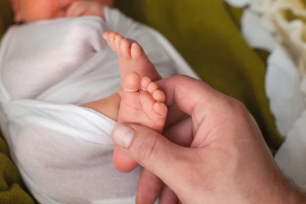 Neugeborene Babyfüße in den Händen des Vaters. — Stockfoto