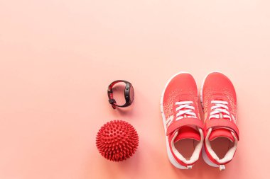 Kırmızı spor ayakkabılar, spor saati ve mercan pembe arka planda pilates topu. Sağlıklı yaşam, spor ve eğitim kavramı, üst görüş, düz alan, kopyalama alanı