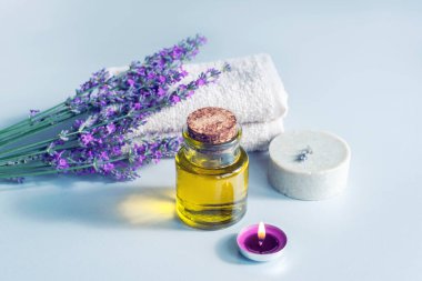 Spa ürünleri, sabun, masaj yağı, mum ve havlu, beyaz arkaplanda lavanta çiçekleri.