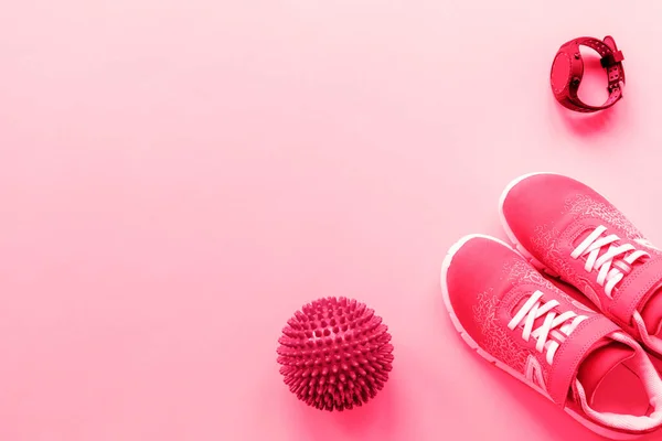 Red sneakers, sport watch and massage ball on pink background. Concept of healthy life, sport and training, top view, flat lay, copy space