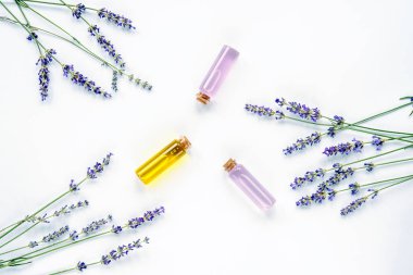 Lavanta çiçeği, özlü cam şişeler ve beyaz arka planda gerekli yağ, üst görünüm, düz uzanma.