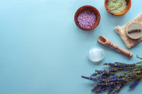 Курортные продукты, мыло, морская соль, цветы лаванды на синем фоне. Вид сверху, плоский, копировальное пространство