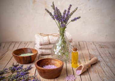 Kaliteli yağ şişesi, havlular ve ahşap masada deniz tuzu bulunan kâseler. Lavanta kozmetik, kaplıca ve sağlık konsepti.