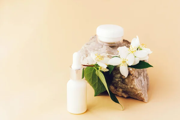 Beauty spa medical skincare and cosmetic lotion cream serum oil mockup bottle with jasmine blossom. Natural stone decor, yellow background.