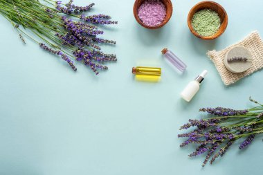 Spa ürünleri, sabun, deniz tuzu, mavi arka planda lavanta çiçekleri. Üst görünüm, düz görünüm, kopyalama alanı.