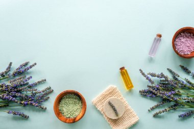 Spa ürünleri, sabun, deniz tuzu, mavi arka planda lavanta çiçekleri. Üst görünüm, düz görünüm, kopyalama alanı.