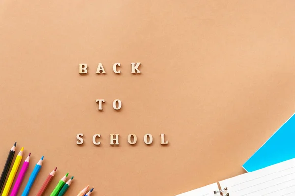 Fournitures scolaires sur fond beige et mots Retour à l'école, pose plate — Photo