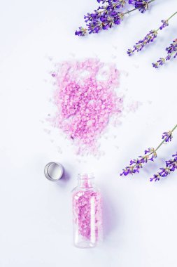 Lavanta çiçeği ve beyaz arka planda bir şişe deniz tuzu, üst manzara, düz yatış.