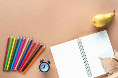 Okul malzemeleri, çalar saat, armut ve açık kahverengi arka planda sonbahar yaprağı. Okul konseptine geri dönelim. Üst görünüm, düz görünüm, kopyalama alanı